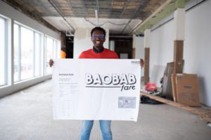 Owner of Baobob Fare holds up a sign in his unfinished shop
